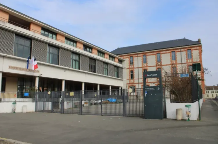 Entrée d’un lycée français avec drapeaux et inscription 'Liberté, Égalité, Fraternité' sur la façade, portail fermé au premier plan.
